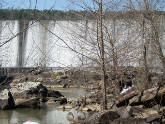 Jerlyn climbing brush to a fishing spot below the dam.